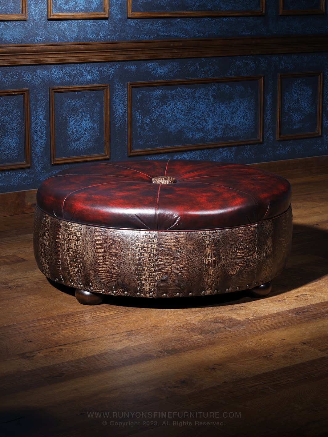 Round oxblood leather ottoman with embossed croc-pattern side panels and wooden bun feet